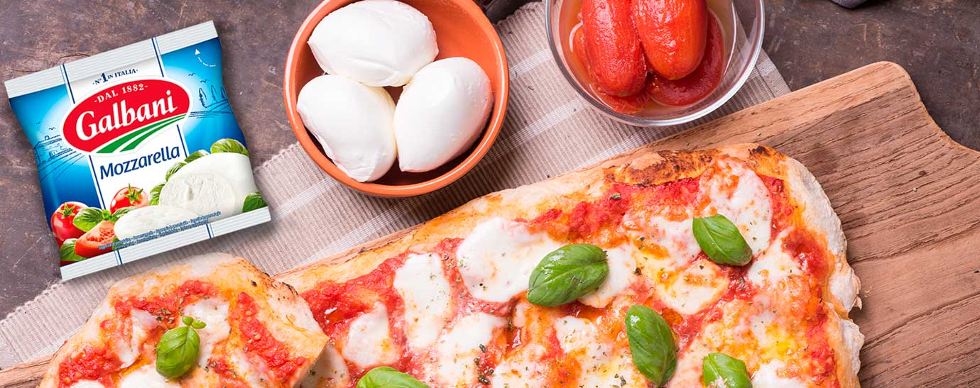 una foccacia con dos cuencos al lado uno de mozarella Galbani y otro de tomate