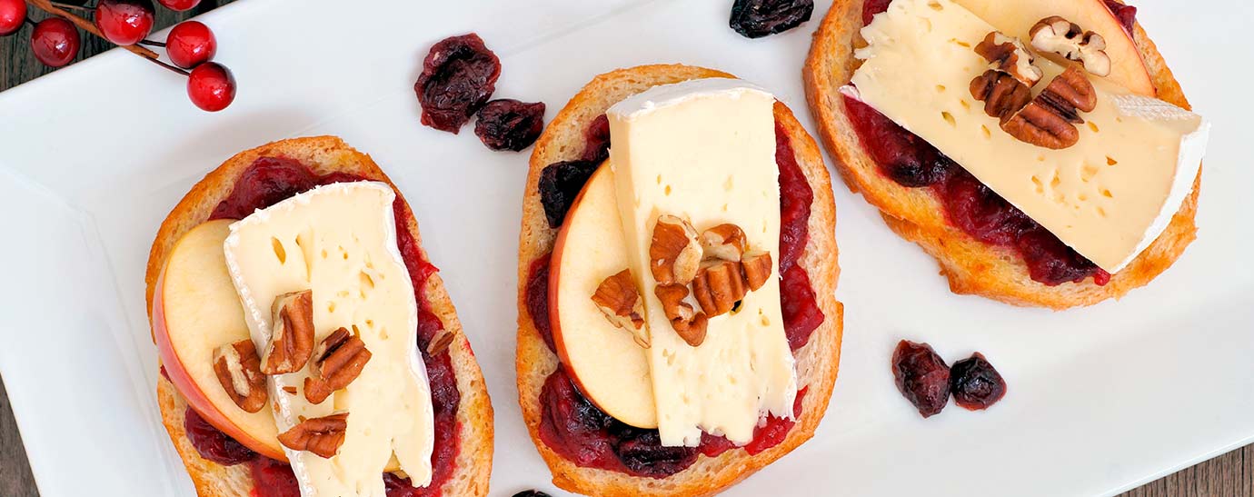 Tres tostas con queso brie con nueces sobre un plato.
