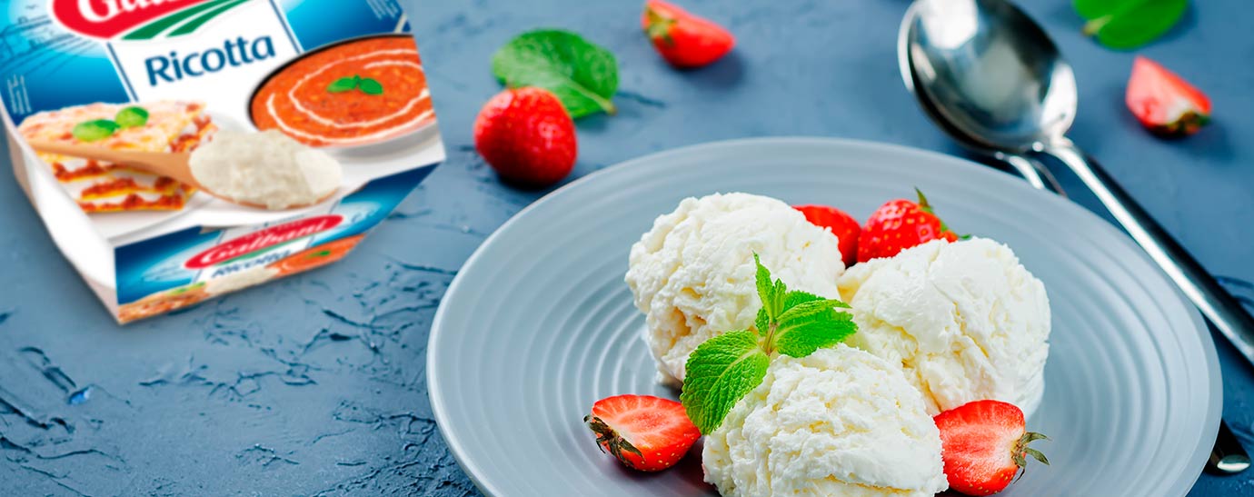 Tres bolas de helado de ricotta con fresas y hierbabuena.