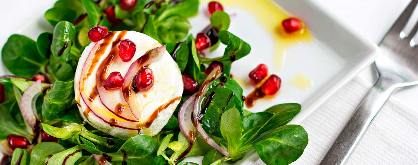 Ensalada con medallón de queso de cabra Président, canónigos, cebolla y granada