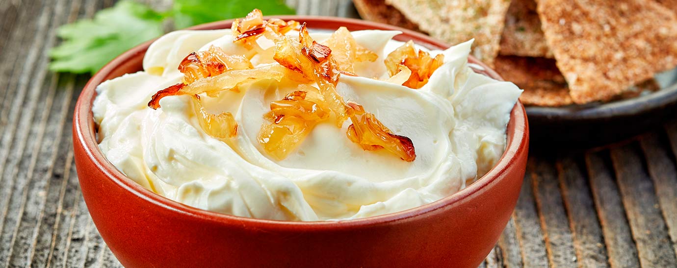 Queso Flor de Esgueva en crema con cebolla caramelizados y chips de semillas