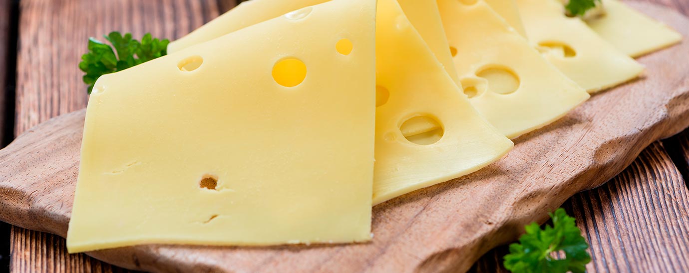 Cuatro lonchas de queso emmental sobre una tabla